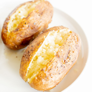 grilled baked potatoes sliced open and placed on a white plate.
