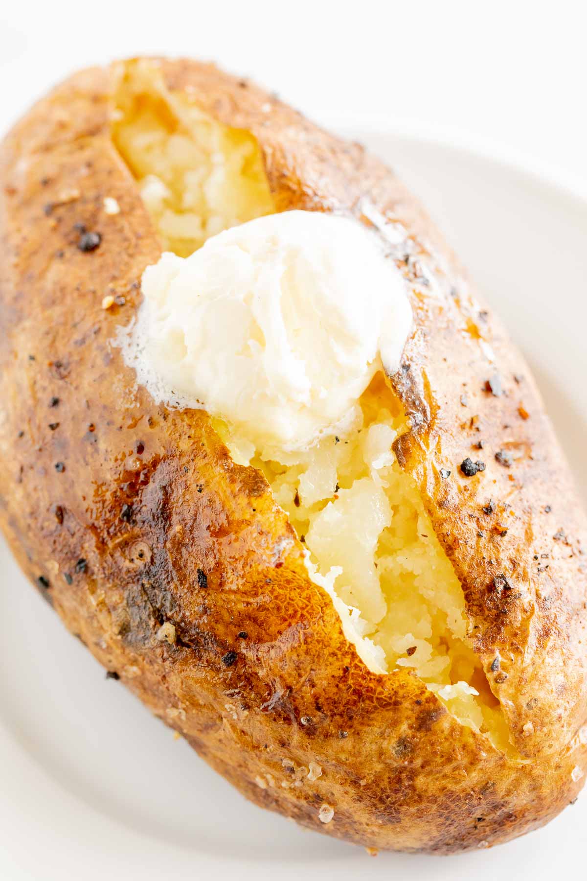 A grilled baked potato on a white plate.