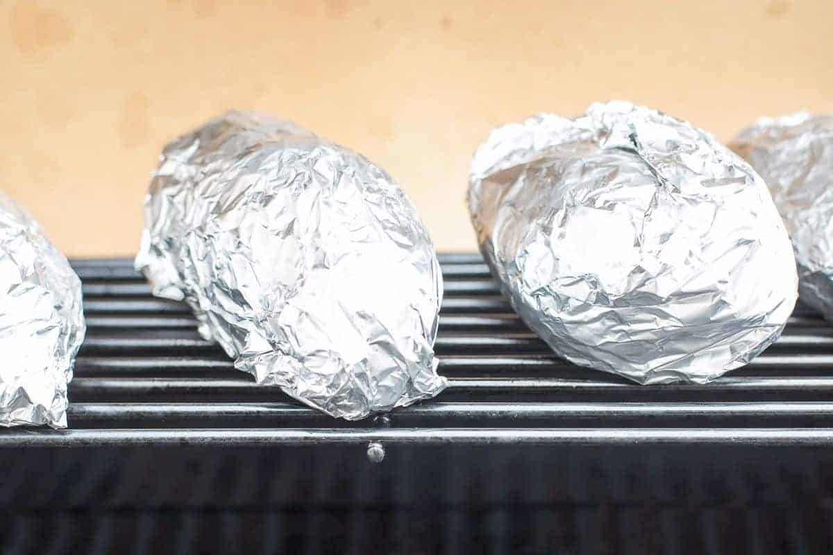 Grilled sweet potatoes in foil on an outdoor grill.