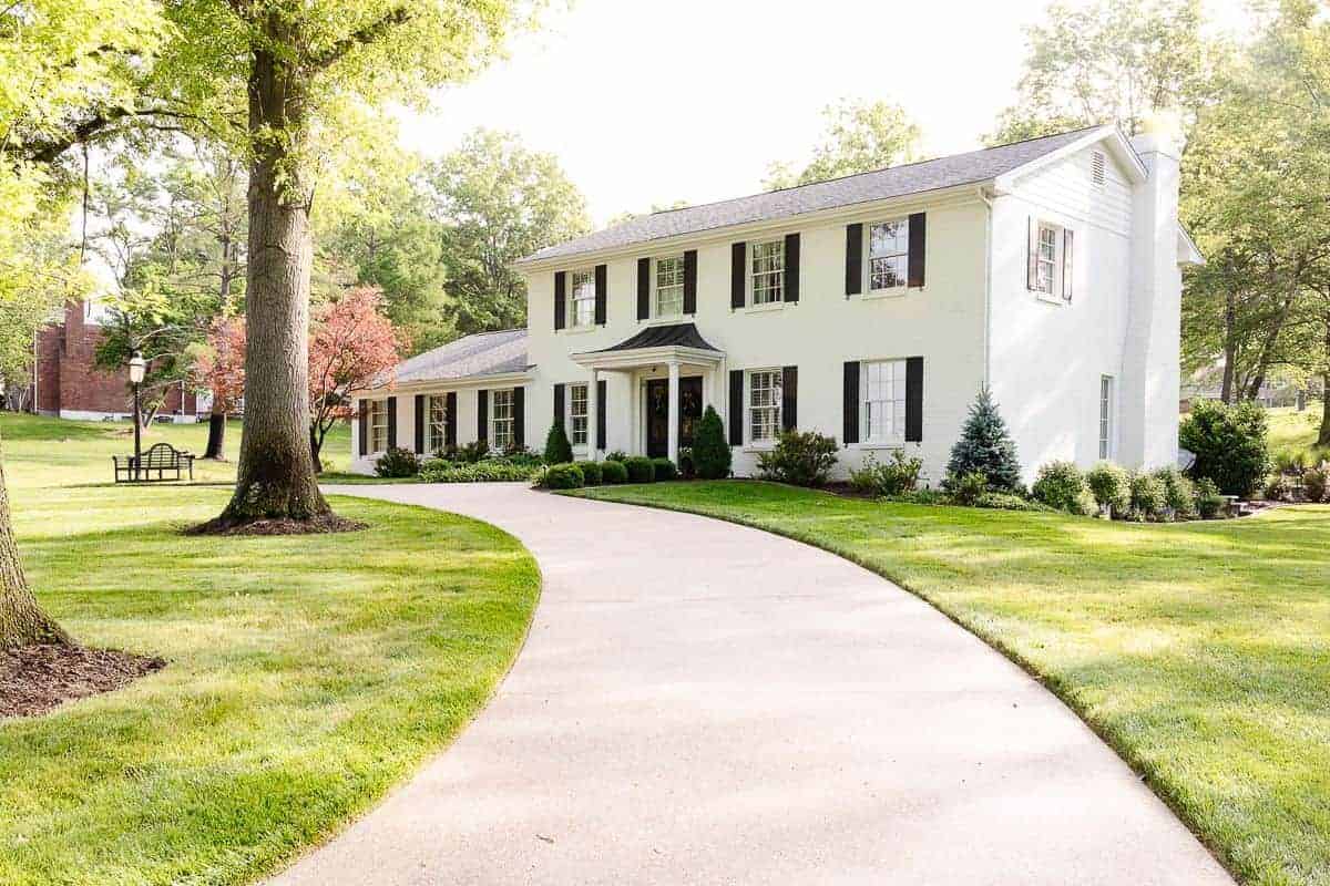 A colonial white brick house with a curved driveway.