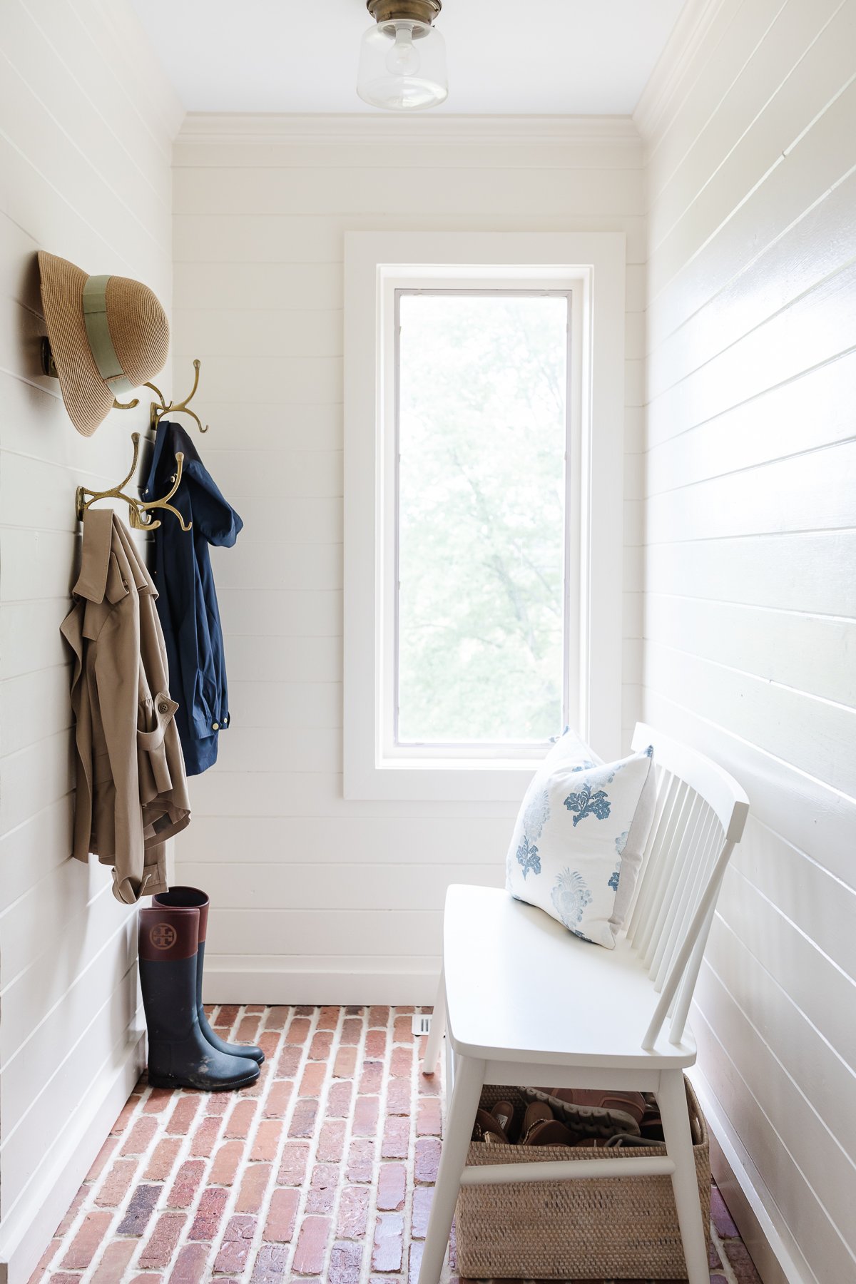white paneled walls in a mud room with brick floors
