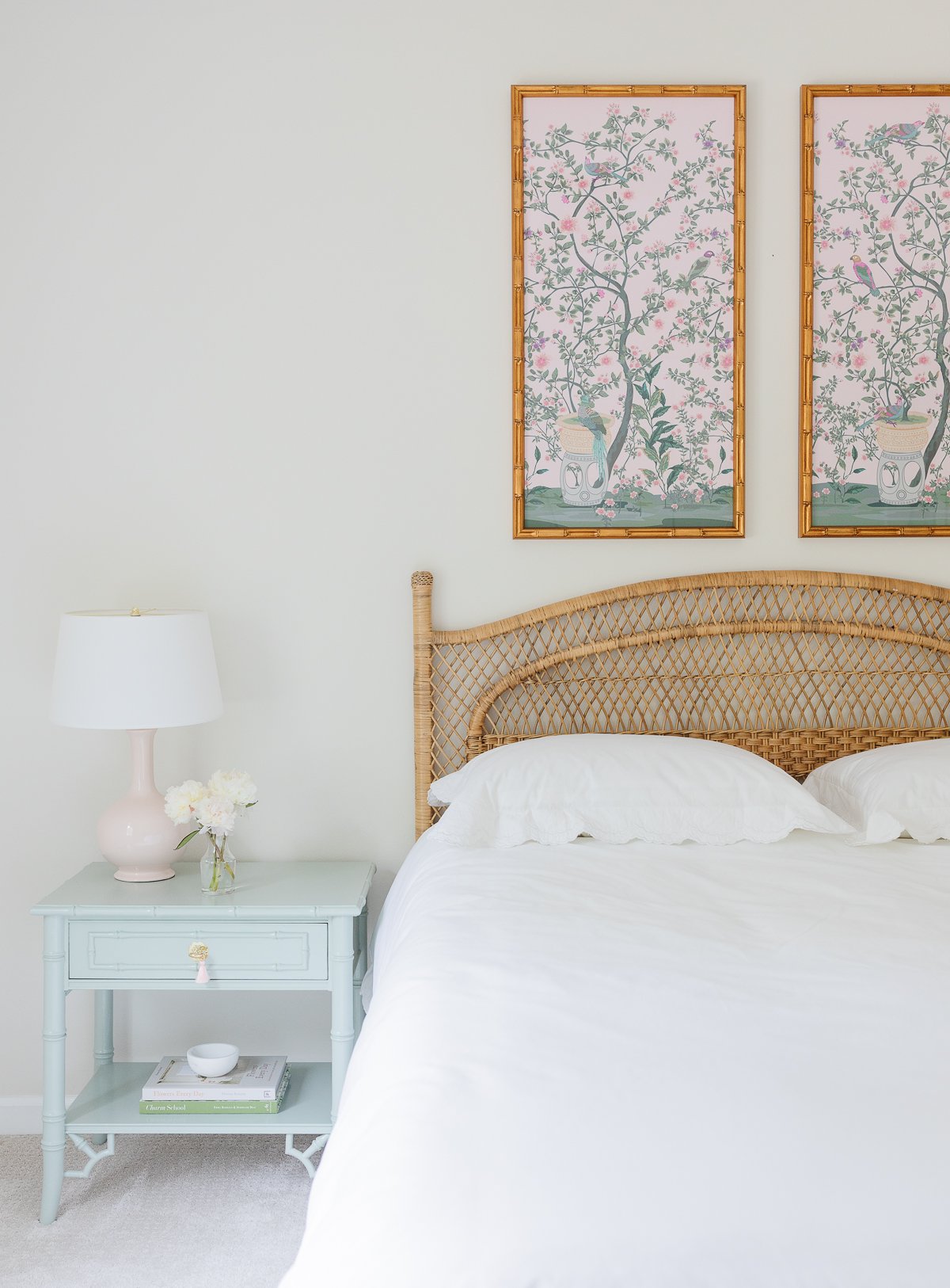 A white guest room with a rattan headboard.