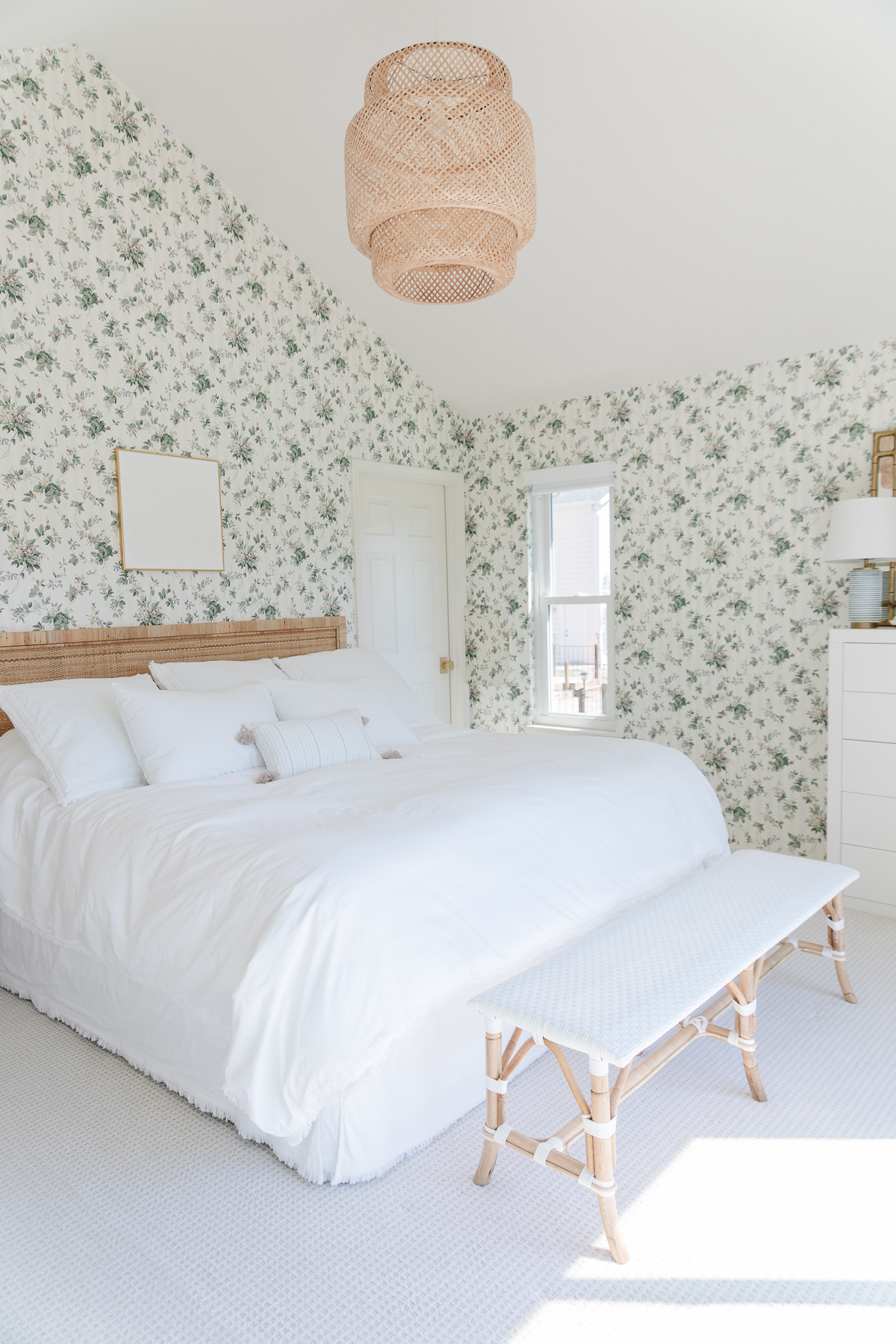 A wallpapered bedroom with a rattan headboard in a guide to luxury home decor for less
