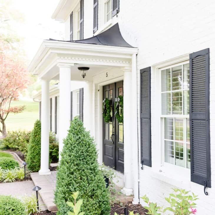 simply white benjamin moore exterior of a colonial home with black shutters.