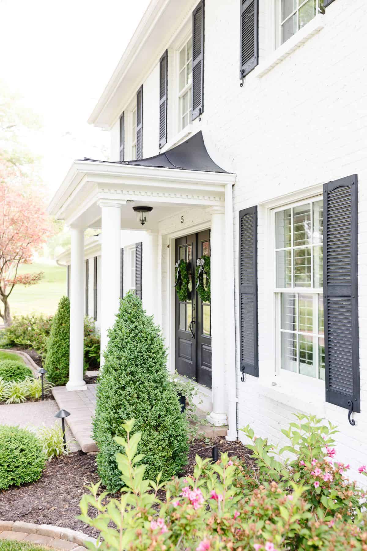 simply white benjamin moore exterior of a colonial home with black shutters.