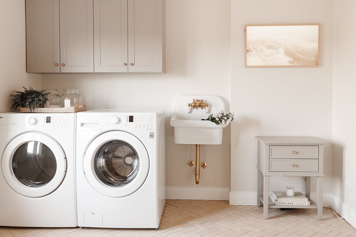 A laundry room with a white washer and dryer and a white farmhouse wall sink.