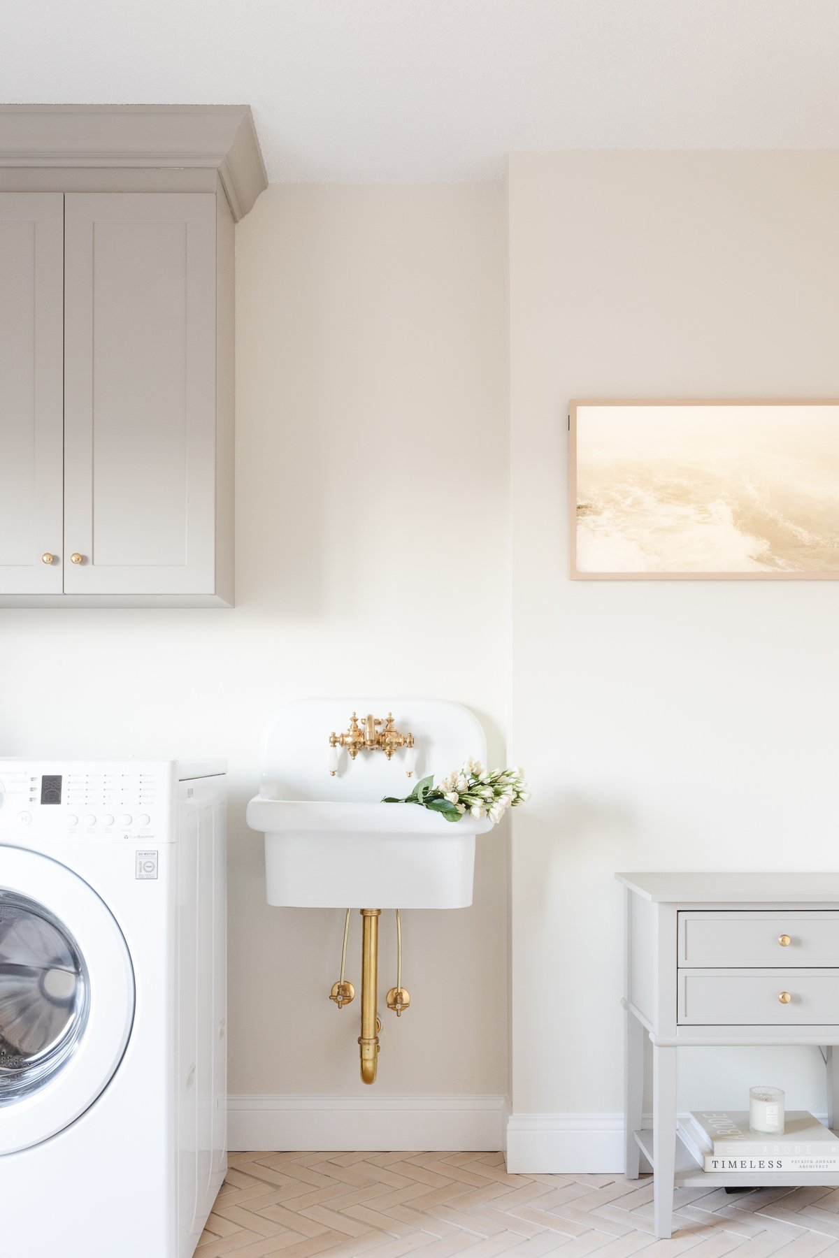 A laundry room with a white washer and dryer and a wall mount farmhouse sink.