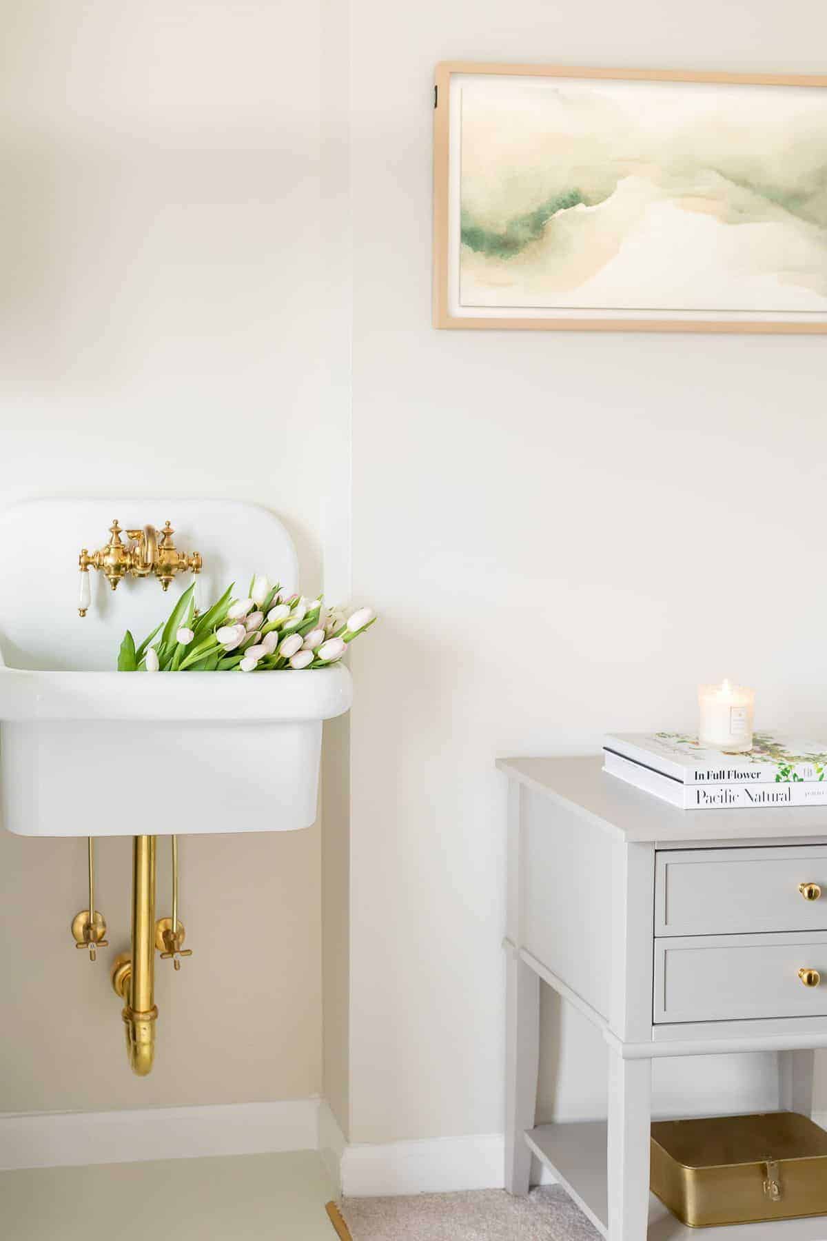 A wall sink filled with white tulips in a laundry room.