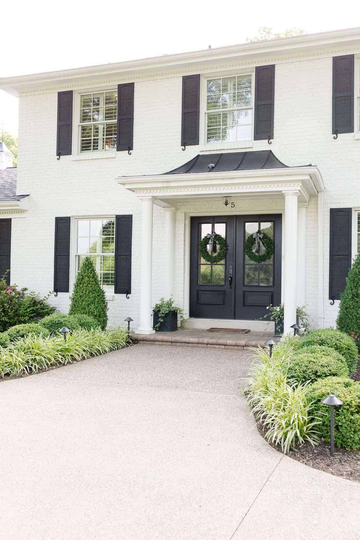 A white brick house with black shutters.