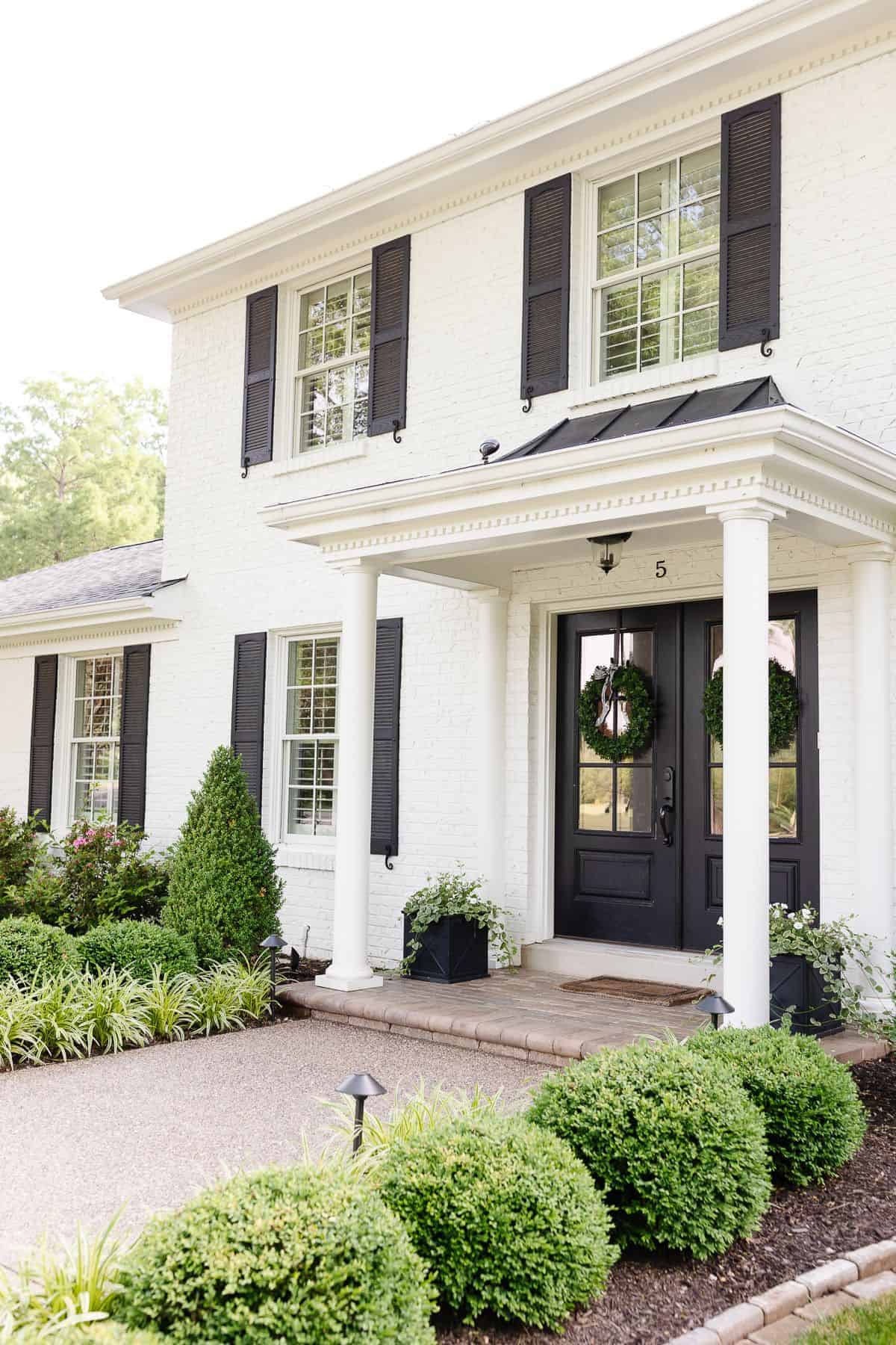 A white brick house with black shutters.