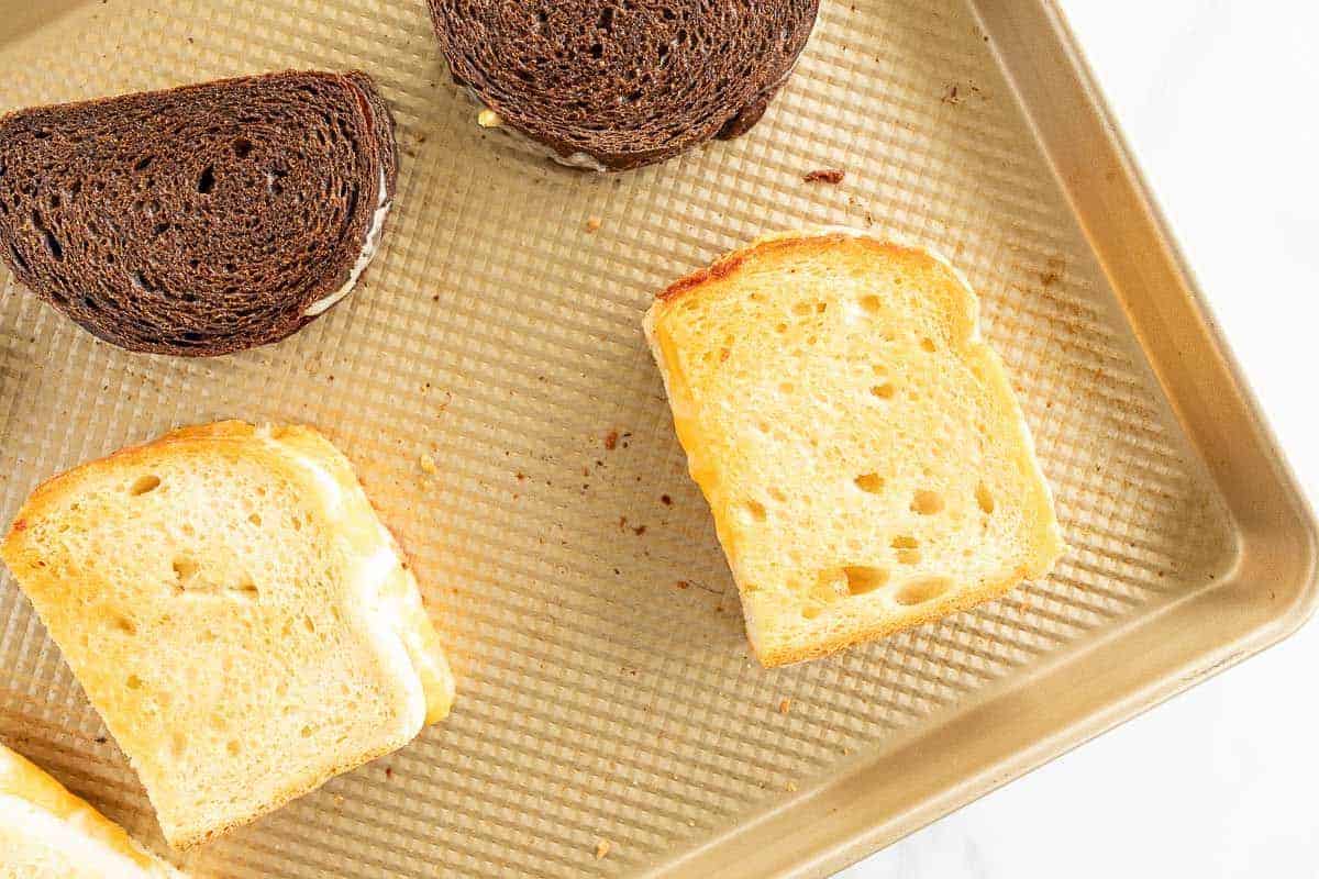 A sheet pan with oven baked grilled cheese sandwiches on top.