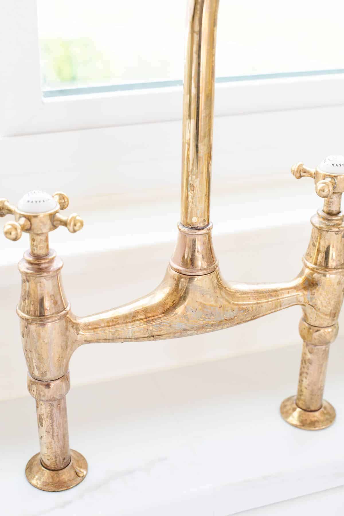 A brass kitchen faucet with some tarnish.