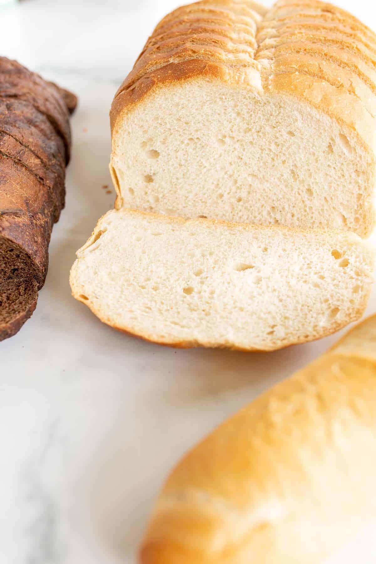 Three loaves of bread on a marble surface.