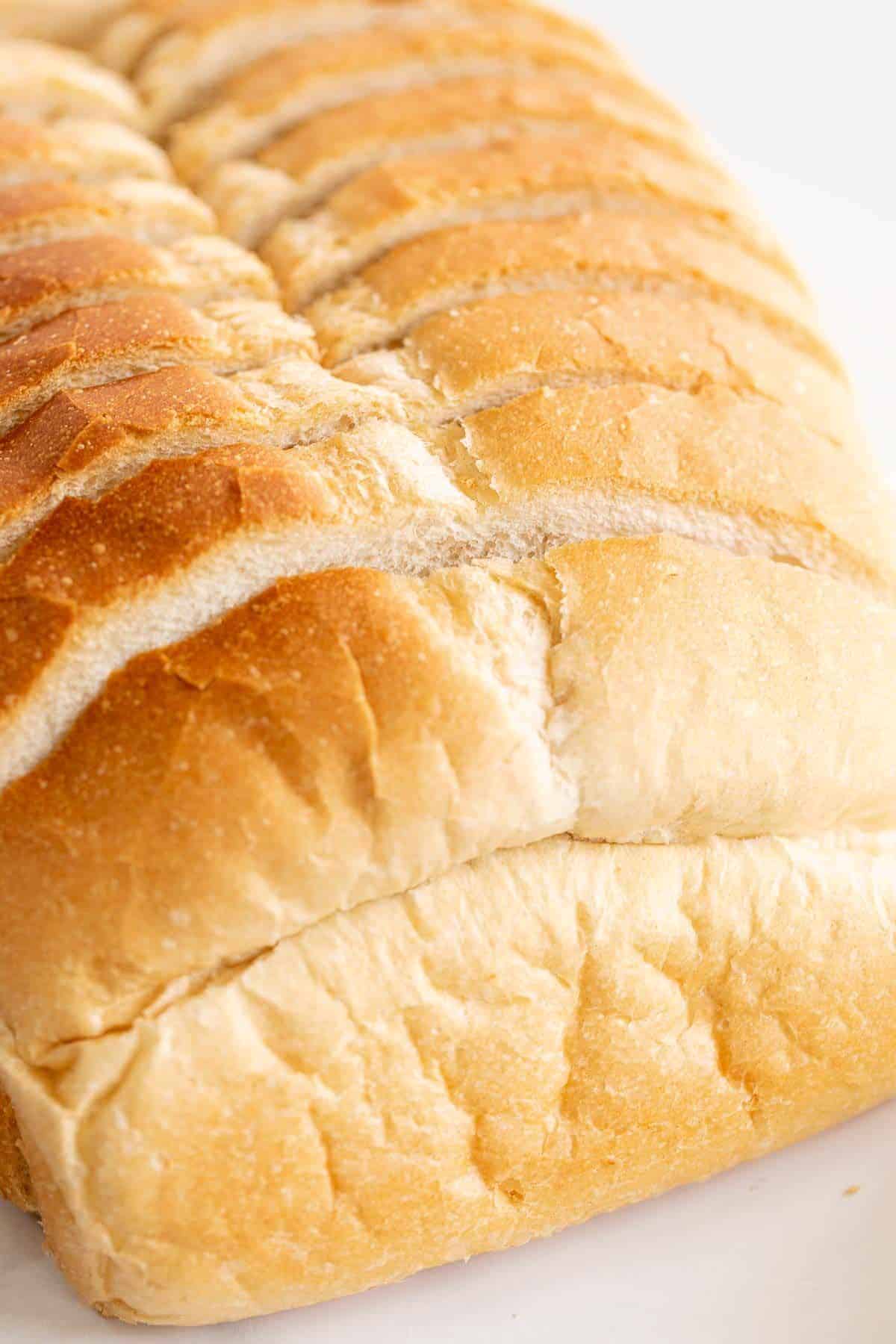 A loaf of classic white sandwich bread, sliced on a marble countertop.