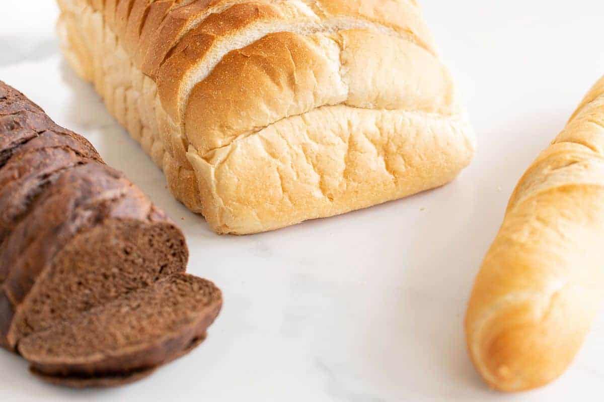 Three loaves of bread on a marble surface.