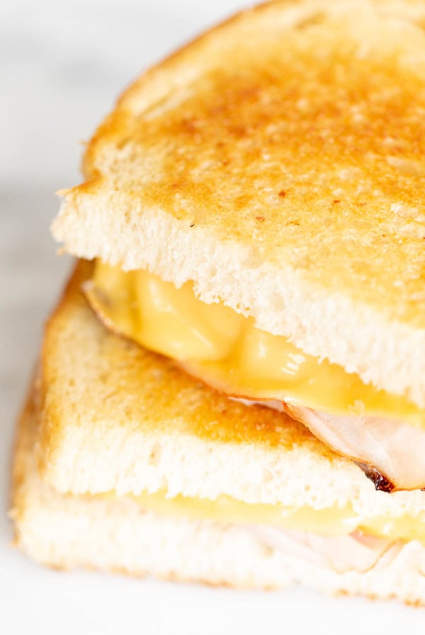 Close-up of a golden brown grilled ham and cheese sandwich with melted cheese and savory ham between two slices of toasted bread.