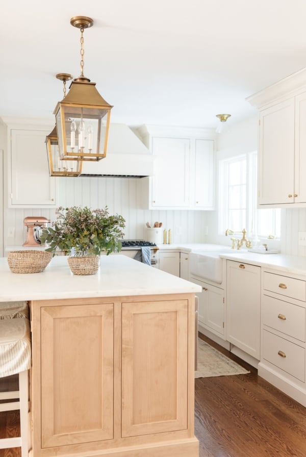 A light oak wood kitchen island with a built in microwave, surrounding cabinets are cream.