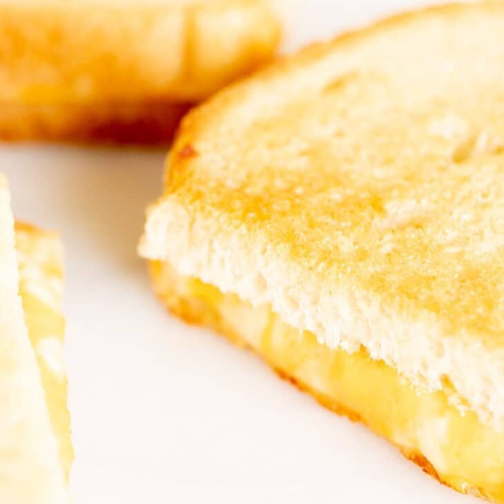 Oven grilled cheese sandwiches, sliced on a white surface.