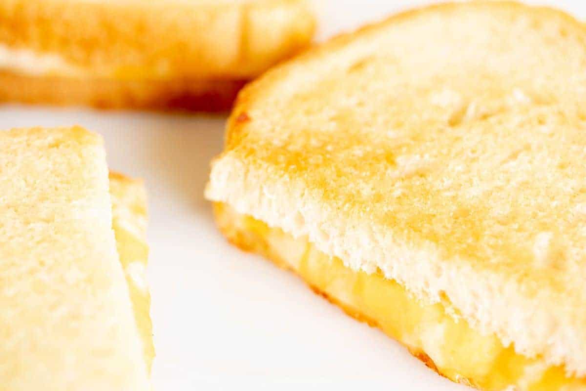 Oven grilled cheese sandwiches, sliced on a white surface.