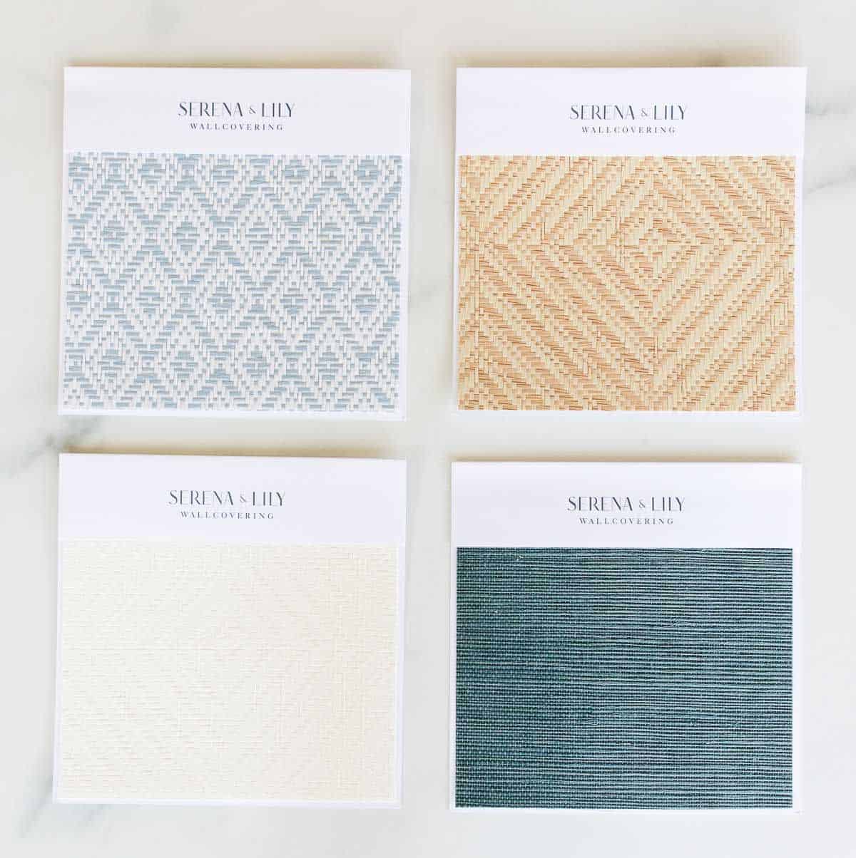 Four wallpaper samples from Serena and Lily laid out on a marble surface.