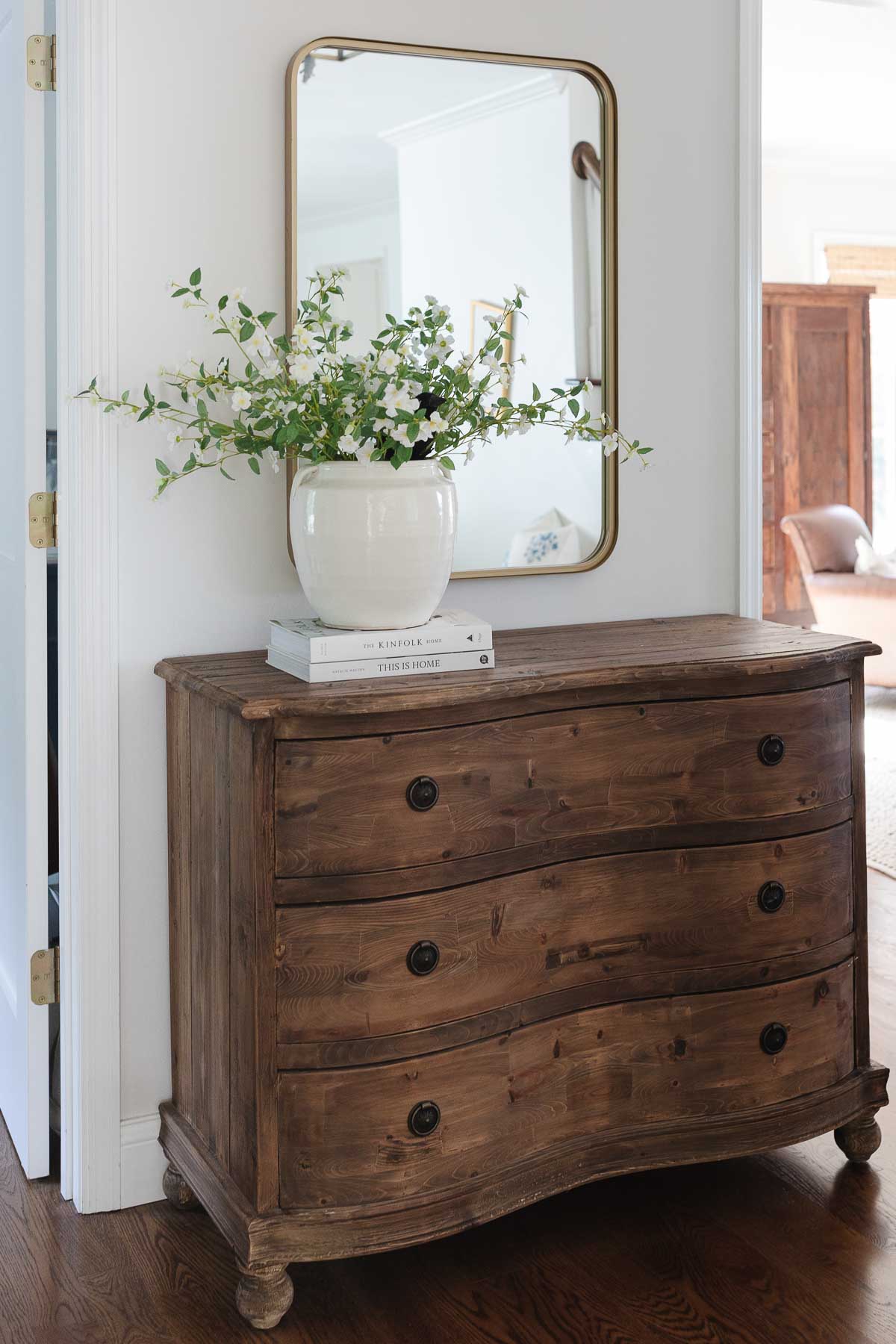 A wooden dresser with a mirror, making the small room look bigger.