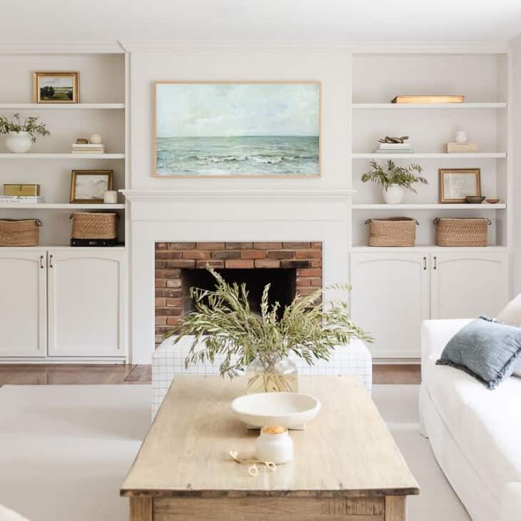 A small white living room with a large cream rug and white walls and furniture.
