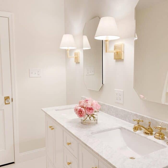 A bathroom with soft white light bulbs in the wall sconces.