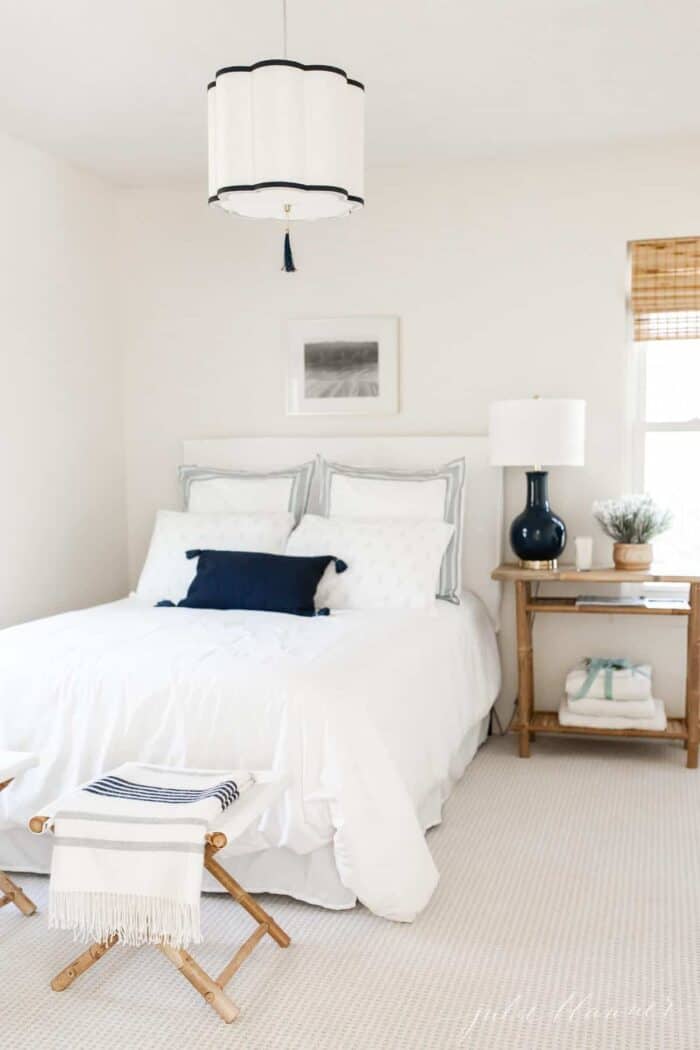 A small bedroom with a navy and white lamp and overhead pendant