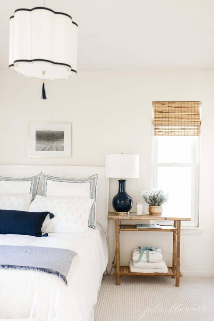 A small bedroom with a navy and white lamp and overhead pendant