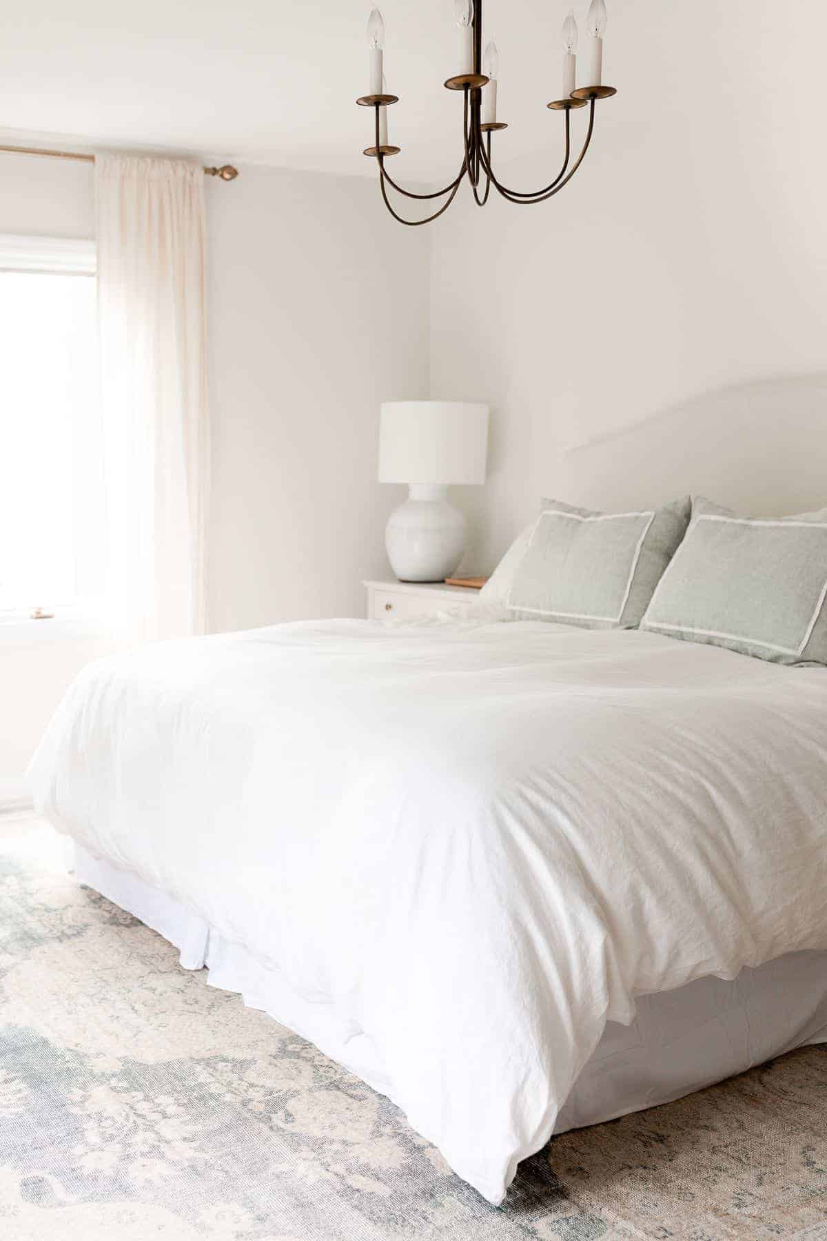 A white bedroom with a large vintage rug under a king sized bed.