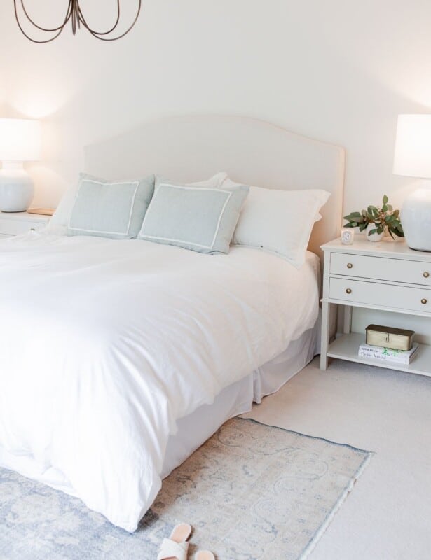 A white bedroom with a bedroom rug placement of a vintage rug under the bed.