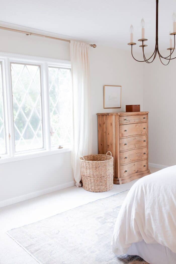 A white bedroom with a bedroom rug placement of a vintage rug under the bed.