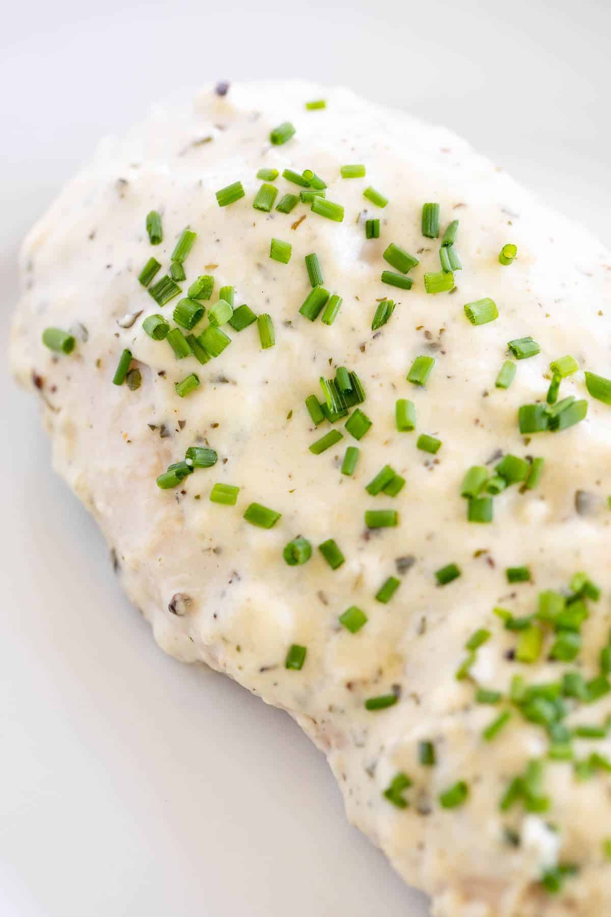 Close up of a baked Boursin chicken breast topped with chopped chives.