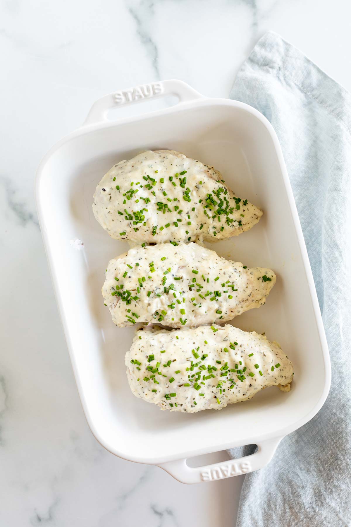 Boursin chicken breasts in a white baking dish.