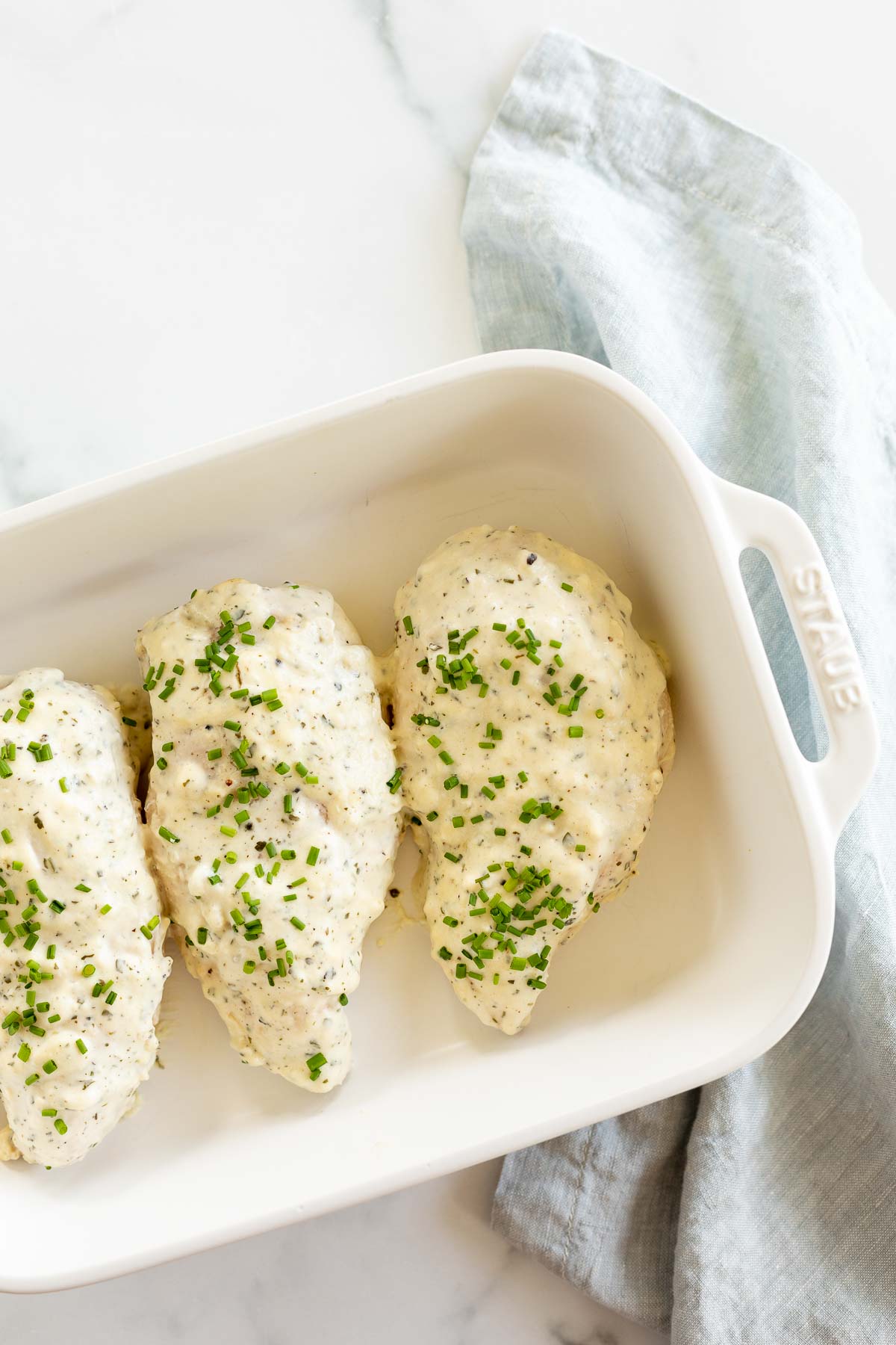 Boursin chicken breasts in a white baking dish.