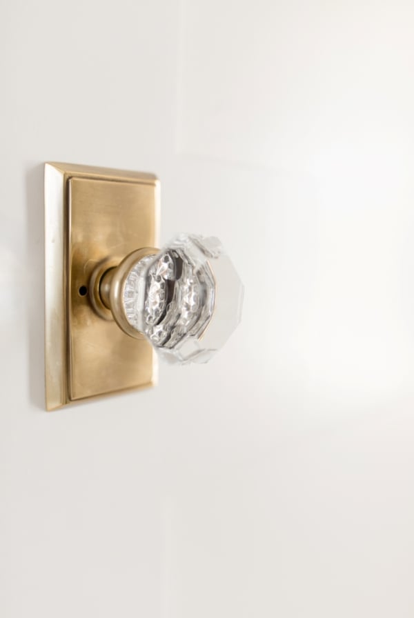 A brass and glass door knob on a cream painted door.