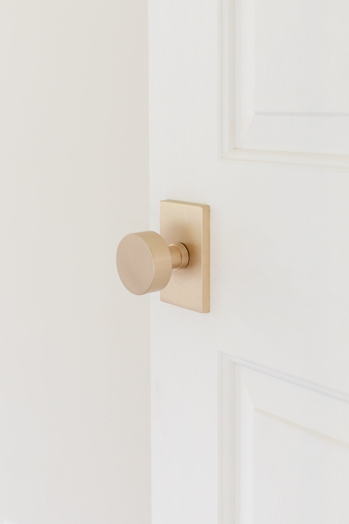 A modern door knob on a white door .