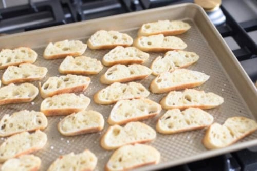 Slices of toasted baguette arranged on a baking tray, perfect for creating delicious crostini.