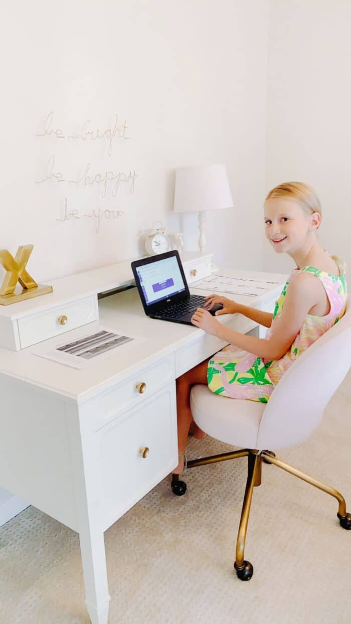 A little girl sitting at a white desk