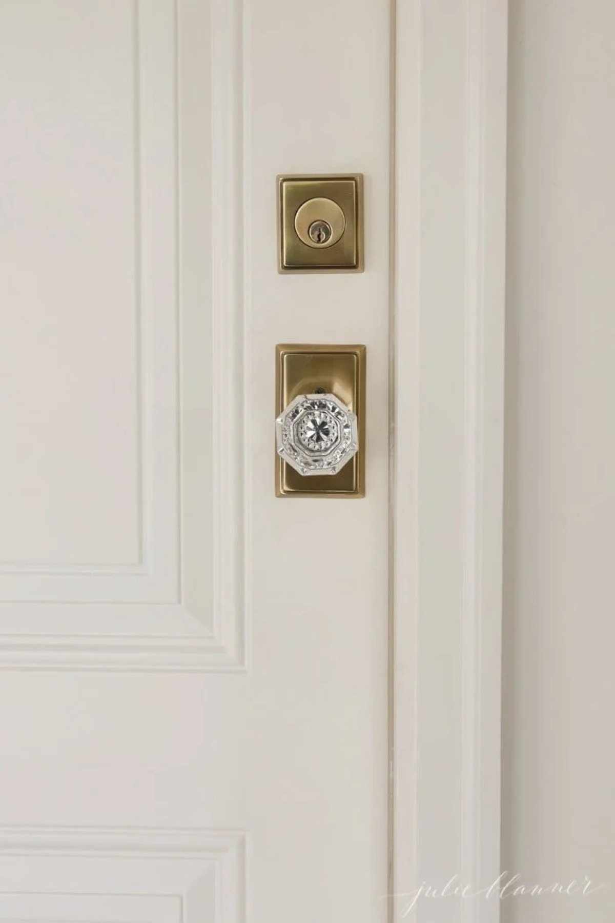 A brass and glass door knob on a cream painted door.