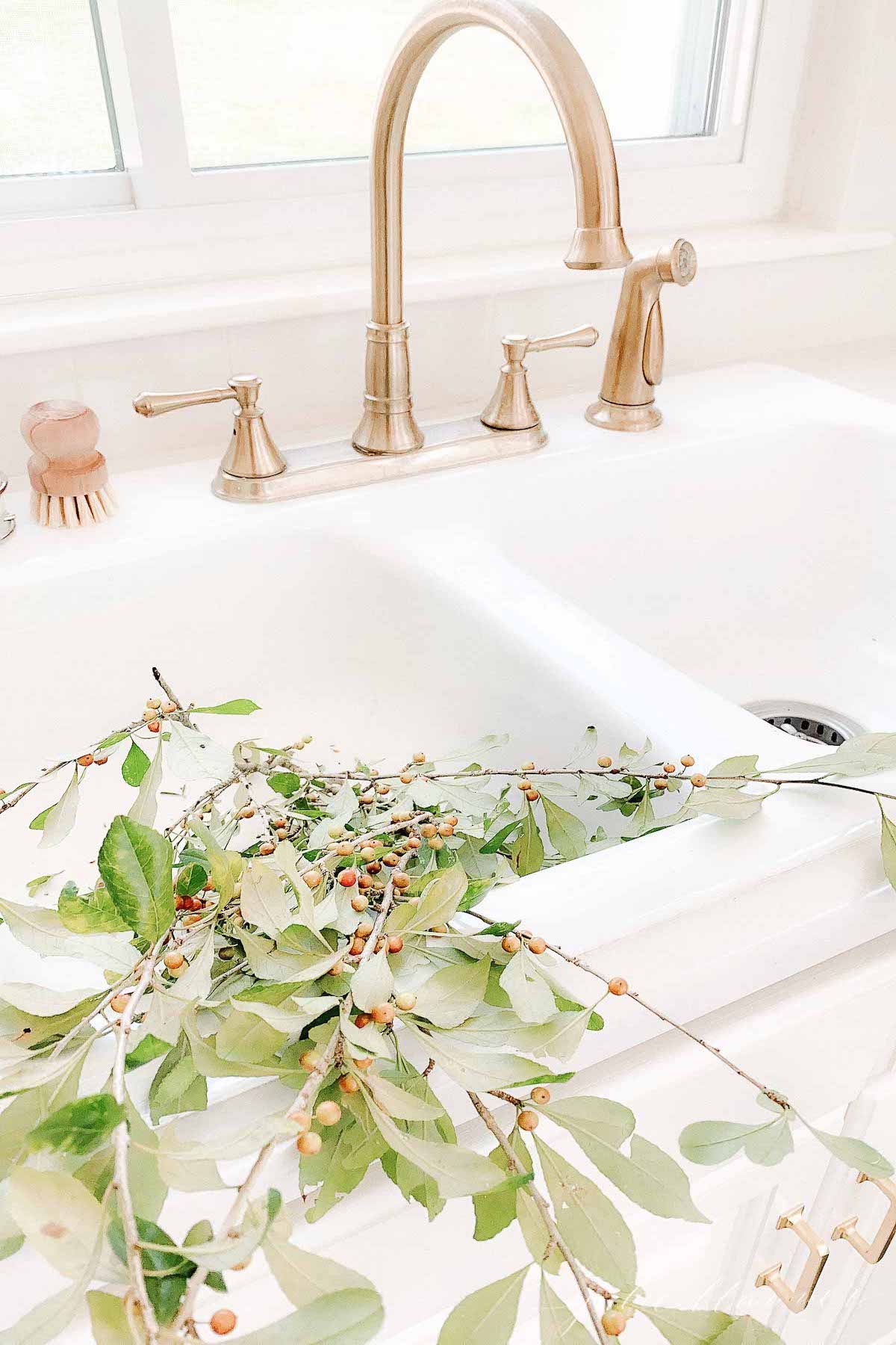 A minimalist kitchen sink with fall branches for minimalist fall decor