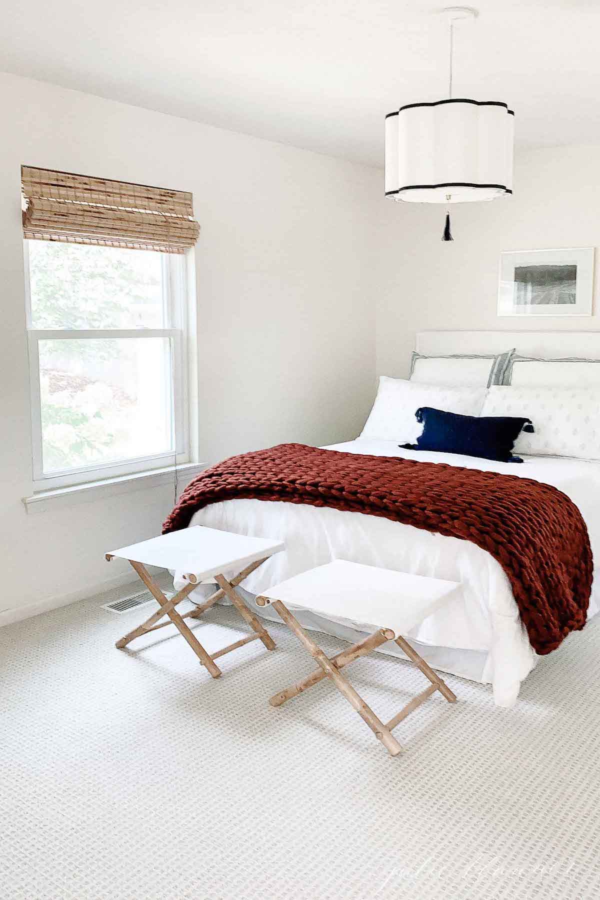 A minimalist white bedroom with a red and white rug.