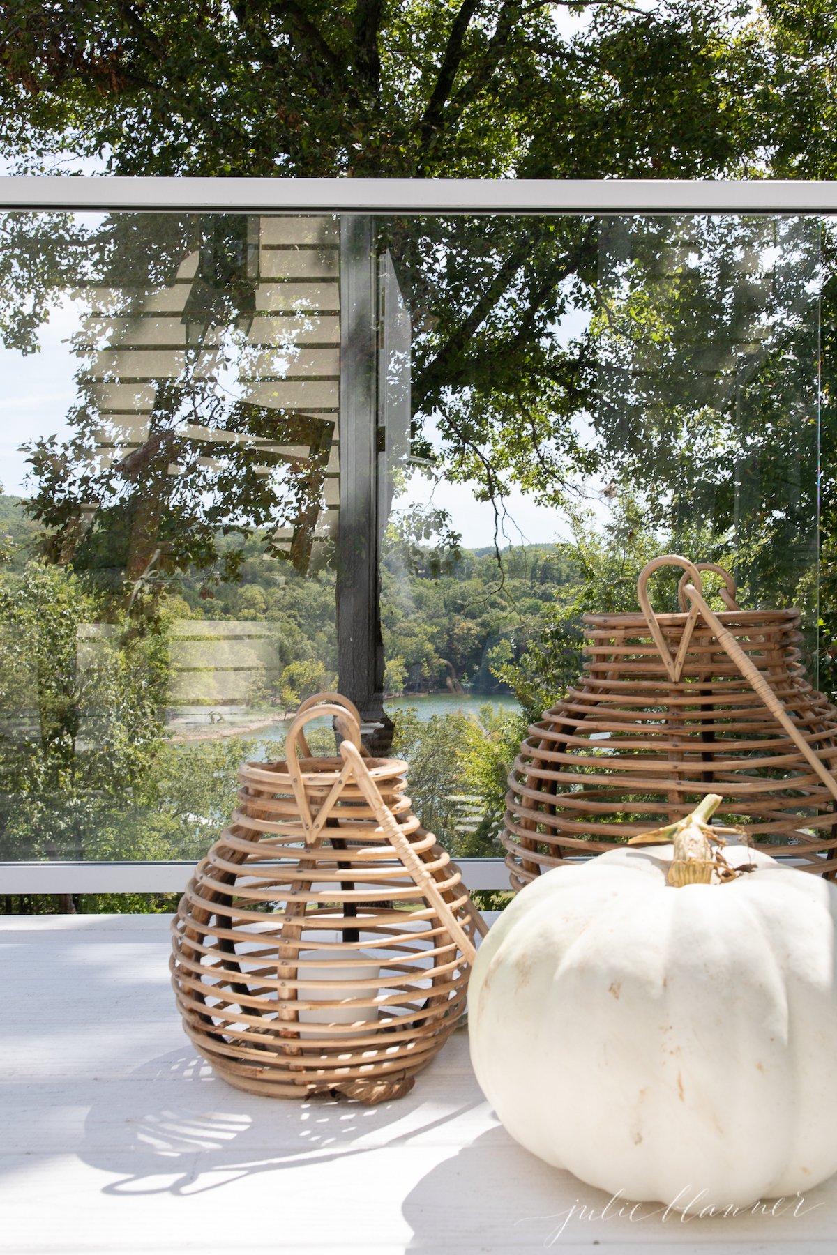 A white pumpkin sits on a table adorned with minimalist fall decor, next to two wicker baskets.