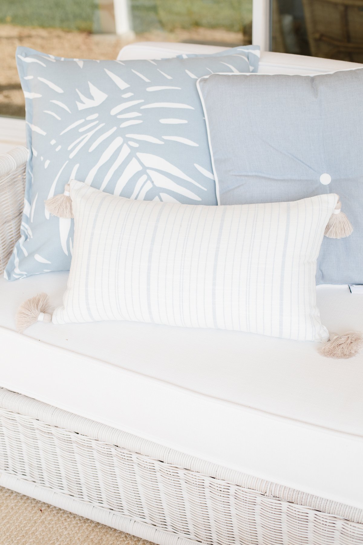 Blue and white pillows on a rattan sofa. 