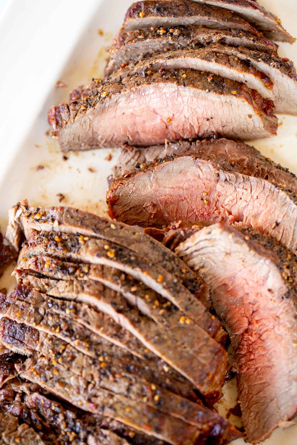 Sliced steak served on a white plate.