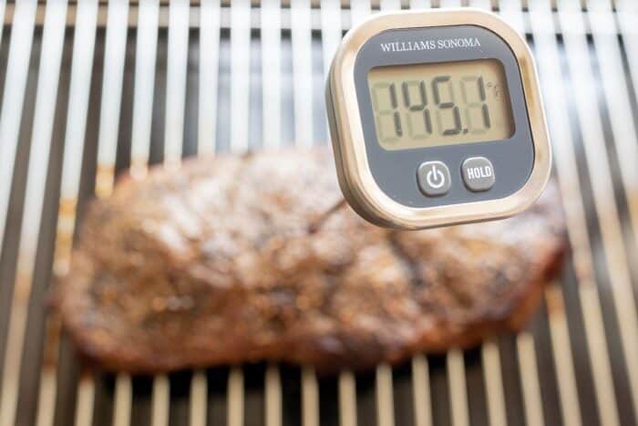 A large steak on a grill, digital thermometer inside reads 145.1