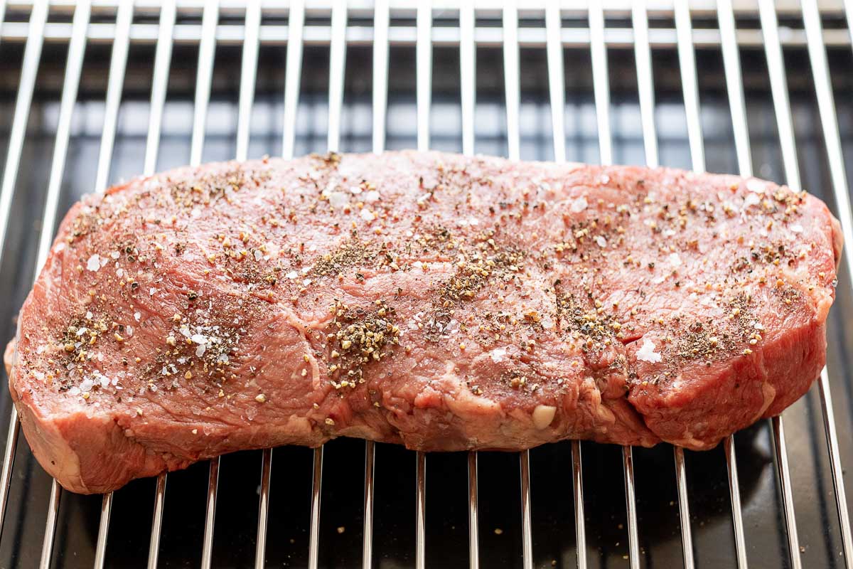 A steak is being cooked on a grill at the perfect temperature.