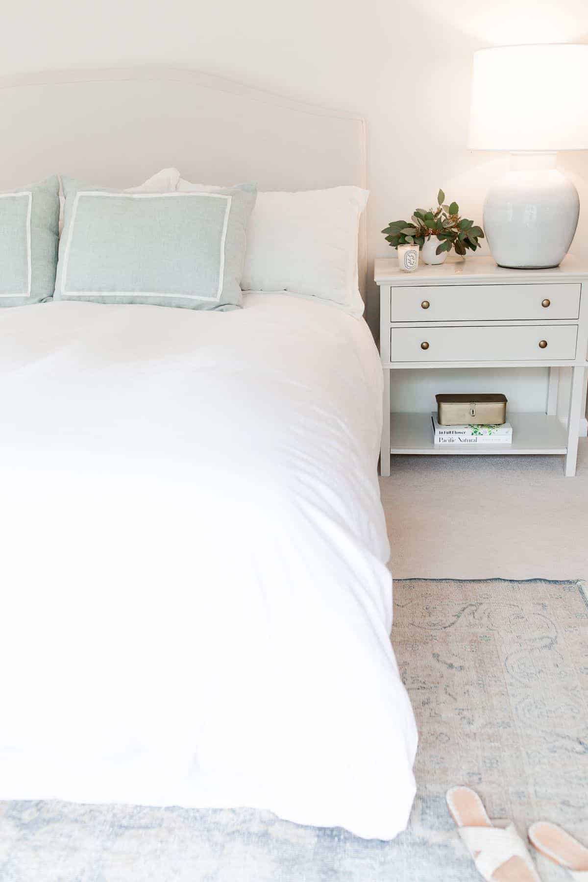 A white bedroom with a bedroom rug placement of a vintage rug under the bed.