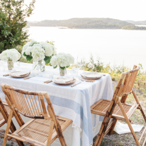 A blue and white table cloth set with bamboo plates and an al fresco dining view.