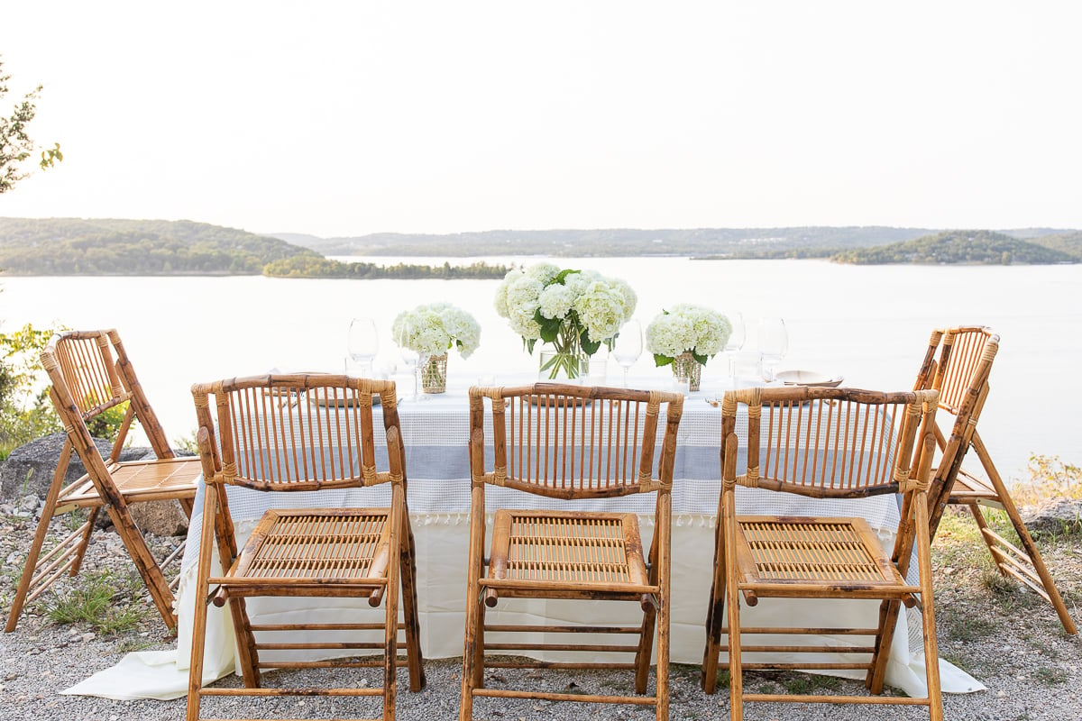 A blue and white table cloth set with bamboo plates and an al fresco dining view.